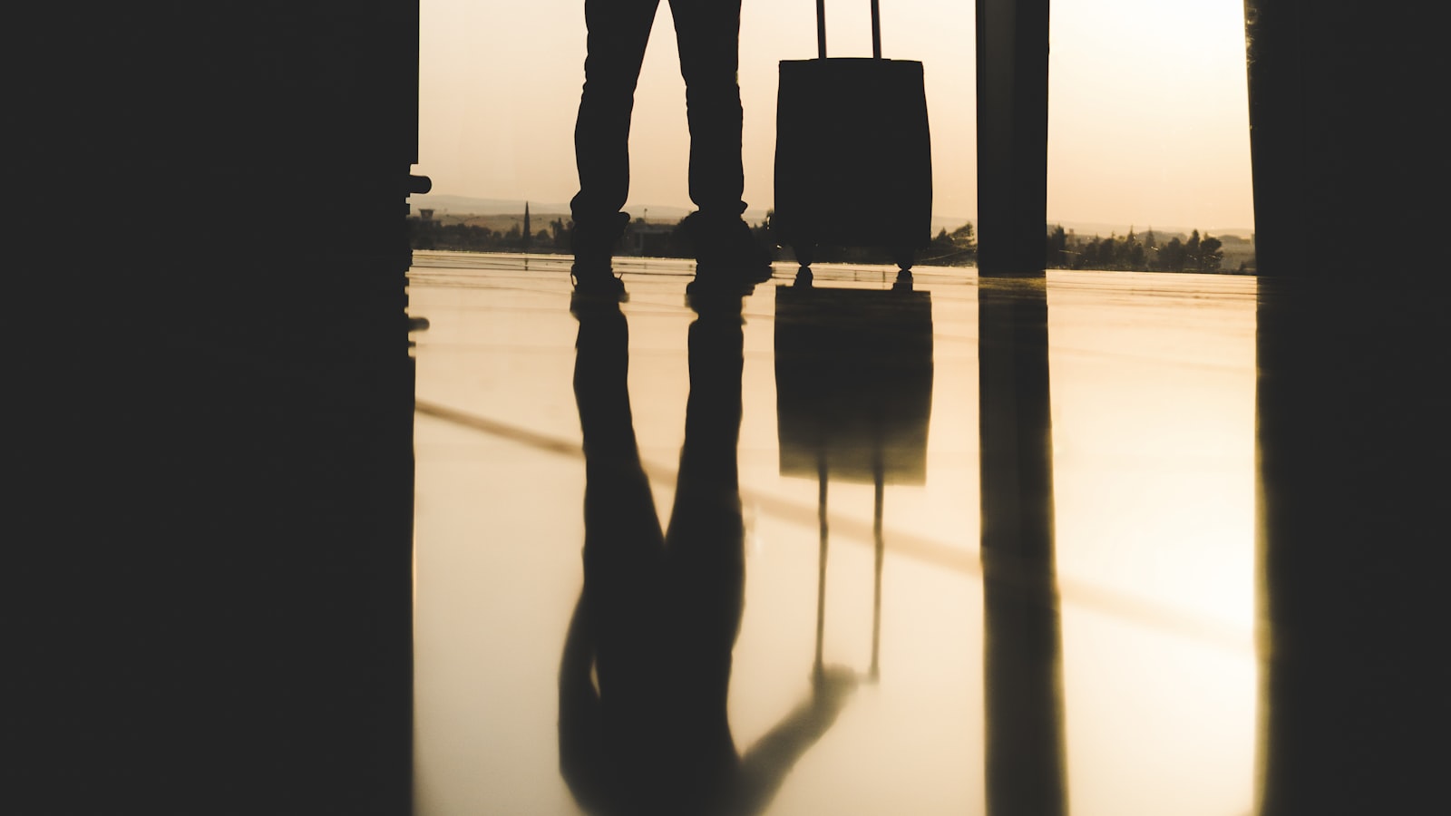A traveler studying a paper map and notebook on a wooden table beside a packed backpack.